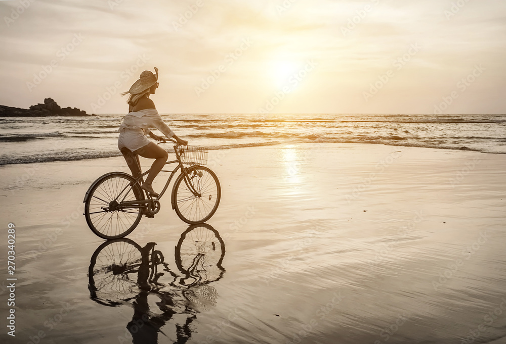 Fototapeta premium Happiness woman traveler with her bicycle rides on sea coastline
