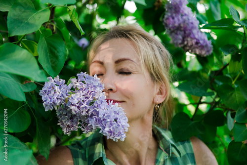 Middle age blond woman in lilac. Portrait of a woman in a flowered garden. woman in summer