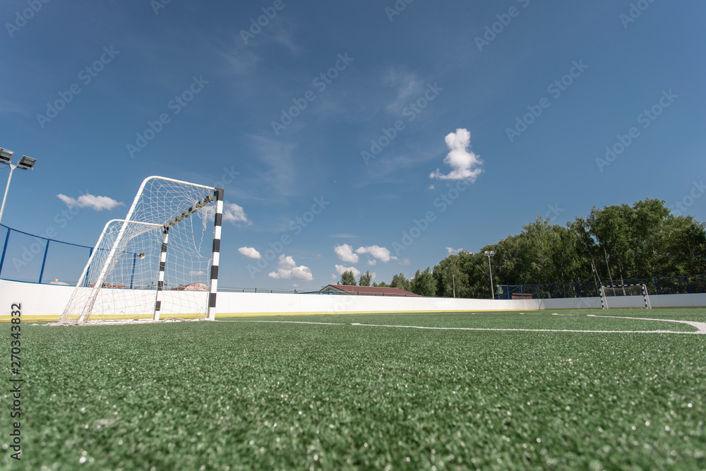 Fototapeta premium Football field. Artificial surface, green grass. Sport outdoors. Goal nets, white lines, circle center.