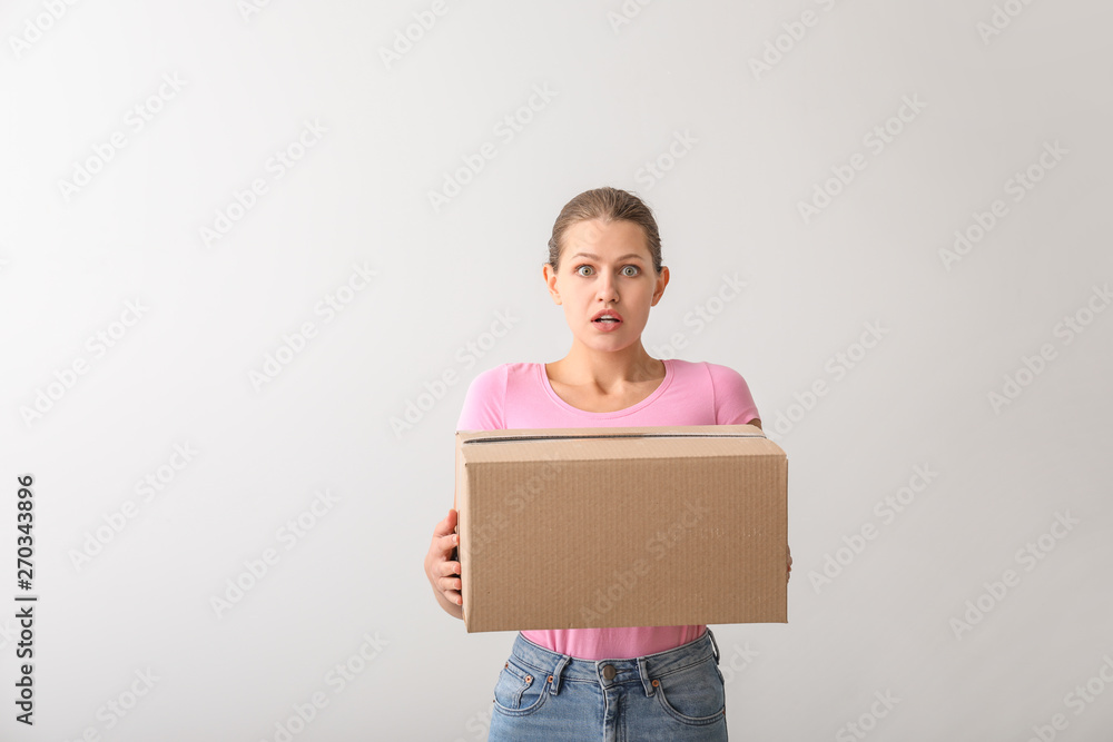 Shocked woman with cardboard box on light background Shocked woman with cardboard box on light background