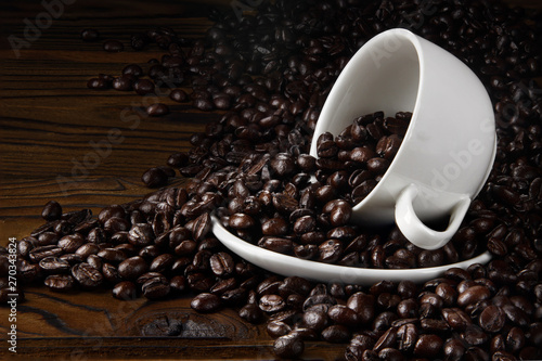 Hot coffee with hot steam and coffee beans on wooden table and old wooden background photo