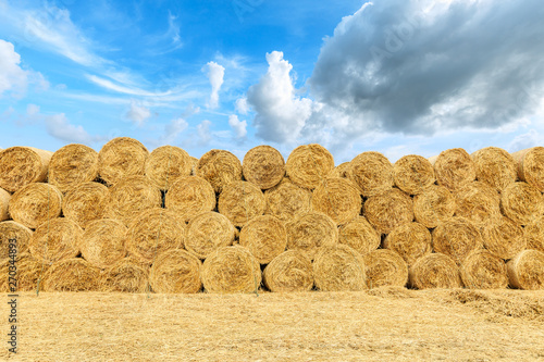 Foto Straw bales on farmland with blue cloudy sky