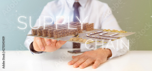 Businessman holding a Supply Chain title with a warehouse on background 3d rendering