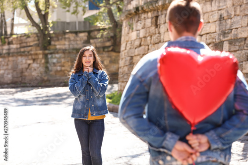 Young man hiding heart shap...