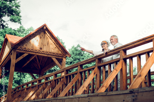 Cheerful spouse standing on the bridge with handsome man