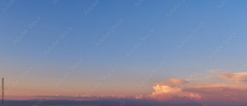 blue sky with clouds at sunset, bright colorful panorama stretching into the horizon