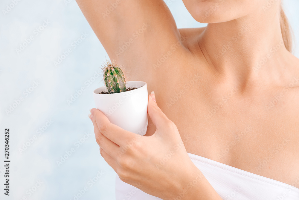 Beautiful young woman with cactus on light background. Depilation concept