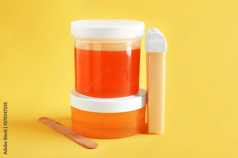 Containers with sugaring paste and liposoluble wax cartridge for epilation on color background Containers with sugaring paste and liposoluble wax cartridge for epilation on color background