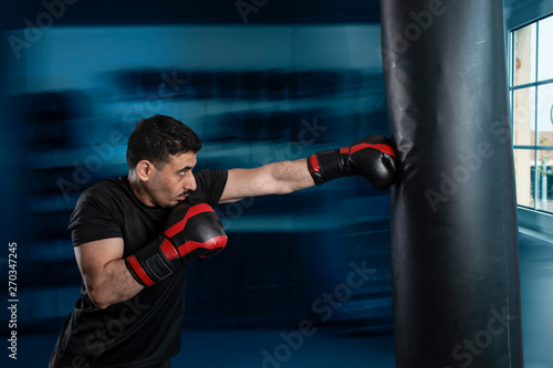 Eastern Arab boxer looks at the box with a punching bag. © igorgeiger