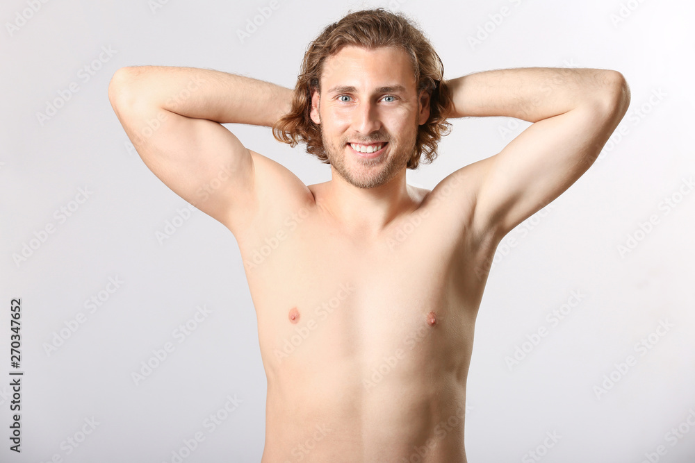 Naked young man after epilation on light background