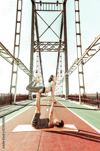 Two people performing acrobatic activities under a summer sky