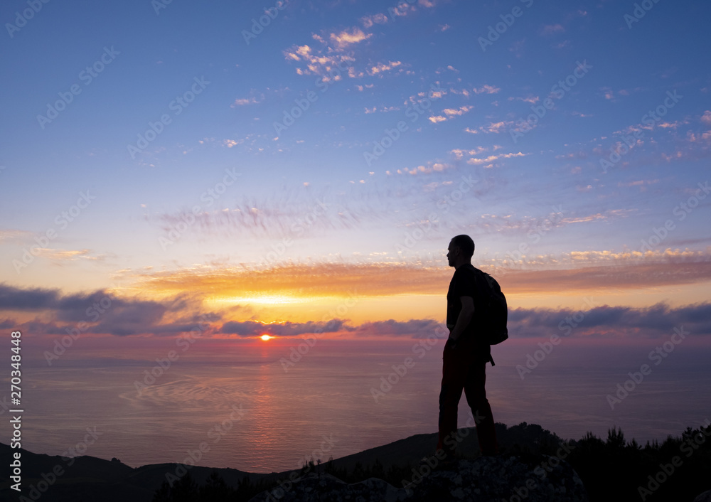 man doing sports with backpack with the sun at sunset over the sea, mount Jaizkibel, Euskadi