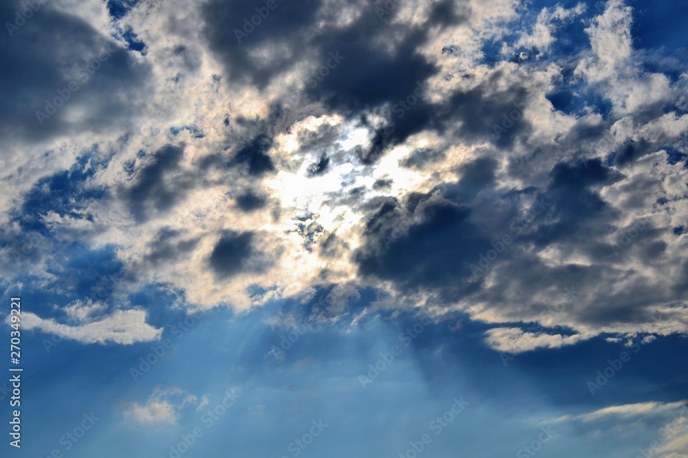 Fototapeta premium Sunbeam piercing through the clouds. Rays of sunshine breaks through the dark clouds. Faith symbol. Hope, faith, optimism concept