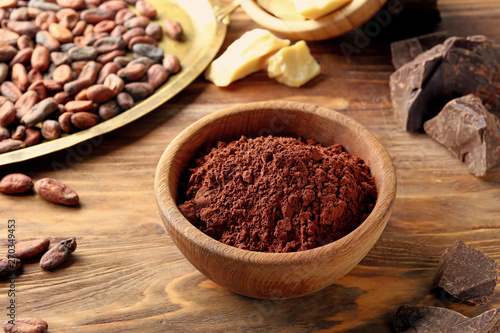 Bowl with cocoa powder on wooden background