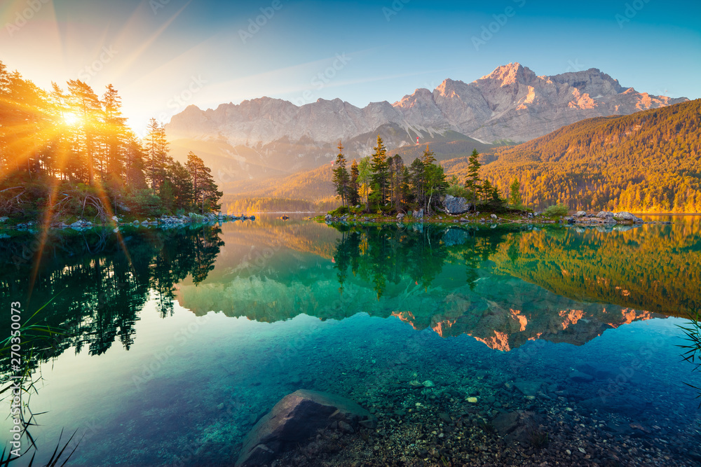Obraz premium Imponujący letni wschód słońca nad jeziorem Eibsee z pasmem górskim Zugspitze. Słoneczna scena plenerowa w niemieckich Alpach, Bawarii, Niemczech, Europie. Piękno natury koncepcja tło.