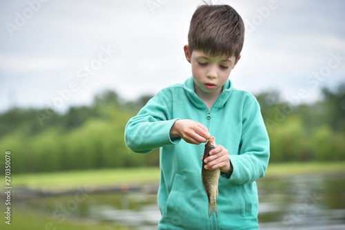 kid boy taking out a hook from the fish