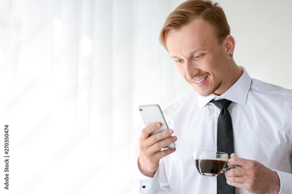 Handsome businessman with phone drinking coffee near window Handsome businessman with phone drinking coffee near window