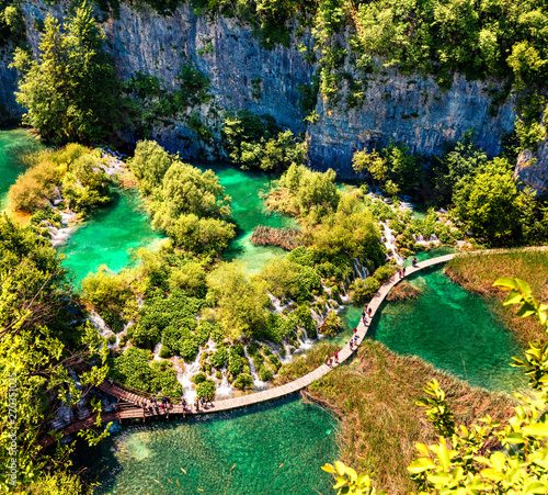 Aerial morning wiew of Plitvice National Park. Colorful spring scene of turists walking on the bridge in green forest with lakes and waterfalls. Great countryside view of Croatia, Europe.
