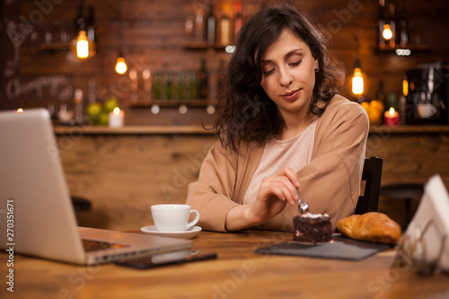 Beautiful woman eating delicious chocolate cake in a coffee shop
