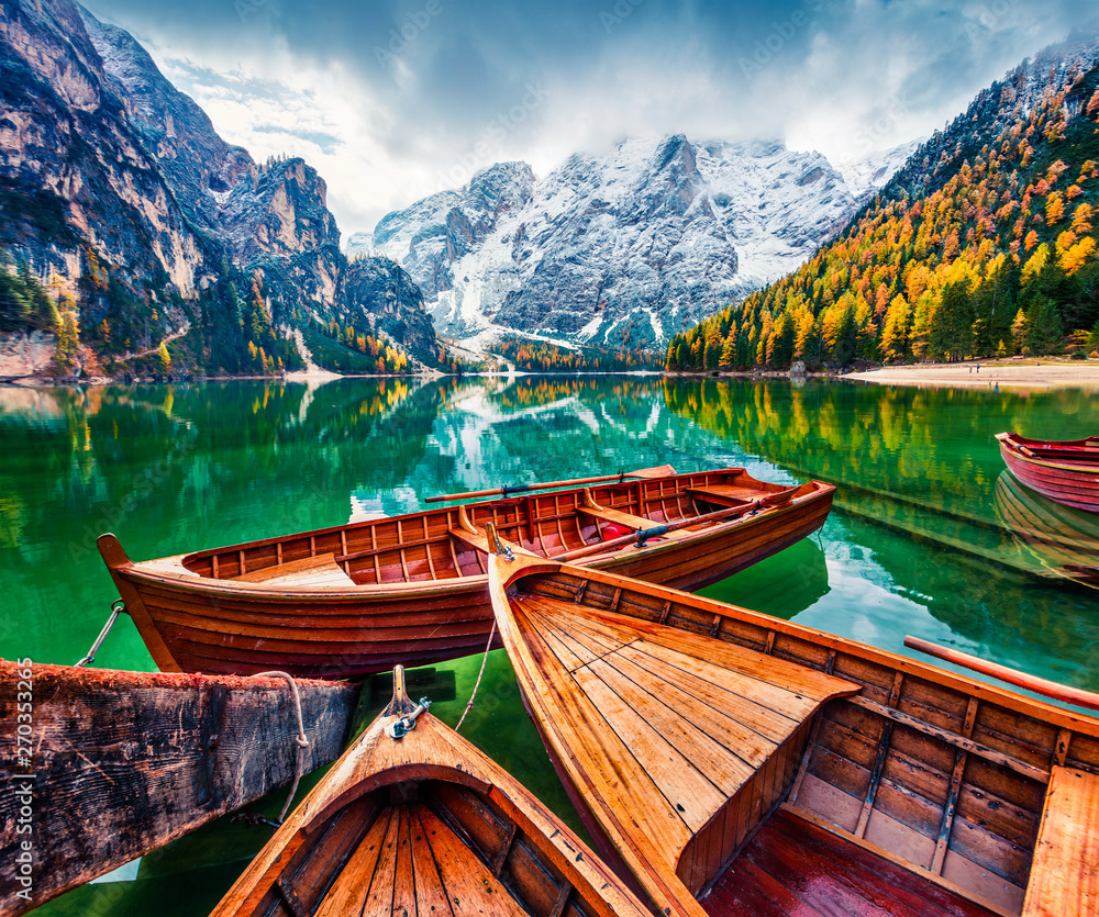Pleasure boats on Braies Lakeand Seekofel mount on background. Colorful autumn landscape in Italian Alps, Naturpark Fanes-Sennes-Prags, Dolomite, Italy, Europe. Artistic style post processed photo.