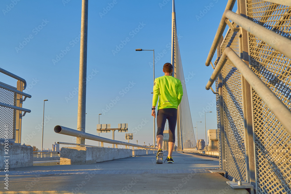 Sportsman working out / jogging on a big city urban bridge. - obrazy, fototapety, plakaty 