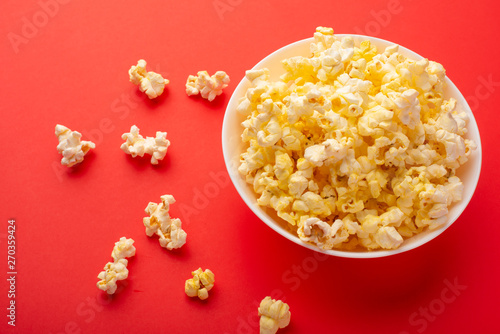 plate with popcorn on a red bright background. movie viewing concept, weekend getaway, with space