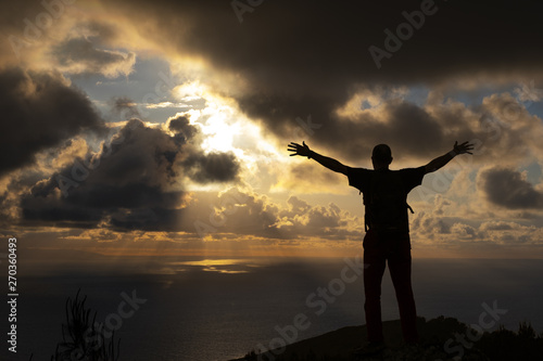 man celebrating victory at the background the sky with clouds at sunset