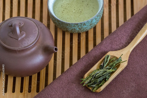 White tea Anji bai cha in a wooden spoon with a teapot and a cup on a bamboo chaban