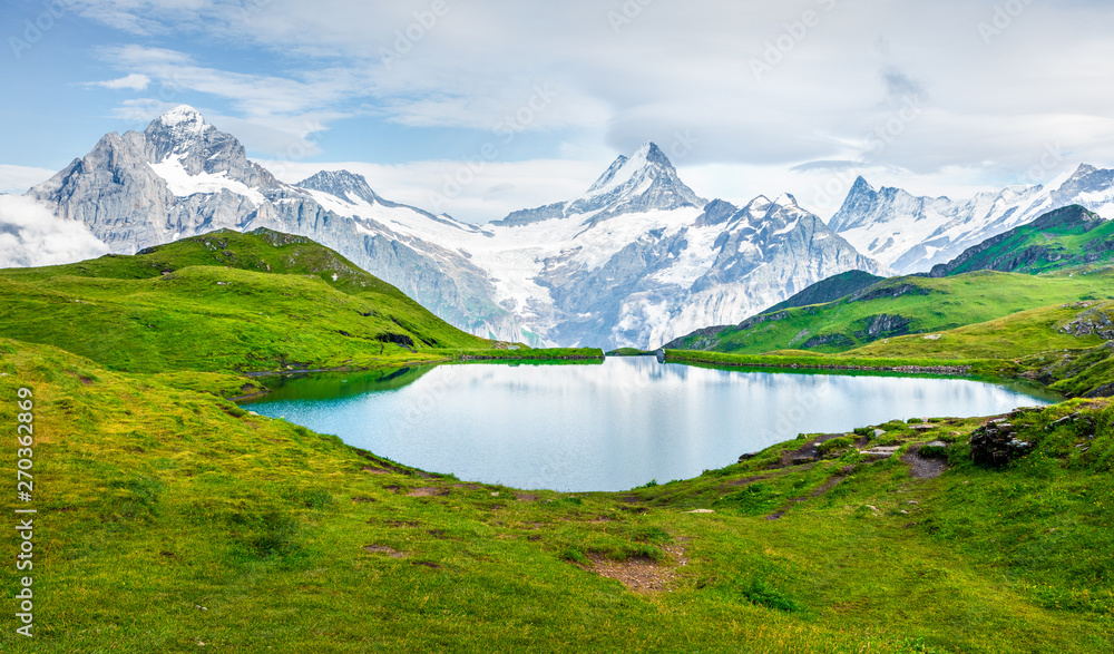 Splendid summer view of the Bachalpsee lake with Schreckhorn peak on background. Colorful morning scene of Swiss Bernese Alps, Switzerland, Europe. Beauty of nature concept background.