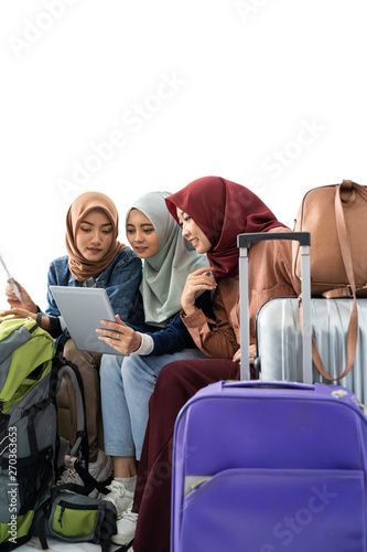 muslim asian woman friend sitting in airport terminal and using tablet