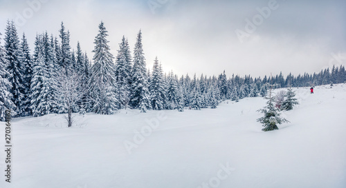 Photographer takes picture in winter mountains. Fantastic morning view of mountain hills with snow covered fir trees. Bright outdoor scene, Happy New Year celebration concept.