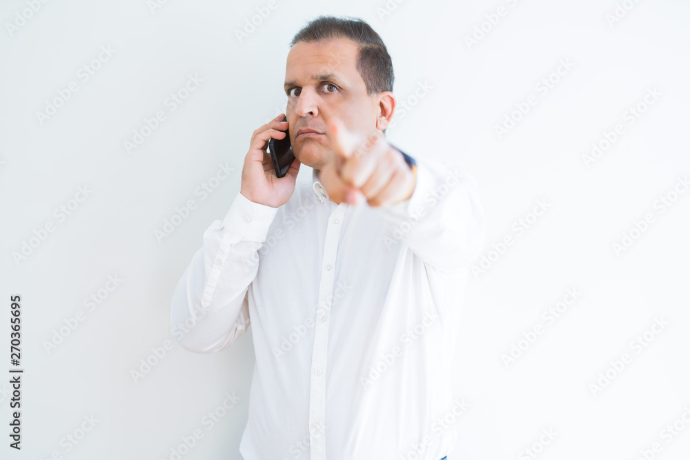 Middle age man calling using smartphone pointing with finger to the camera and to you, hand sign, positive and confident gesture from the front Middle age man calling using smartphone pointing with finger to the camera and to you, hand sign, positive and confident gesture from the front