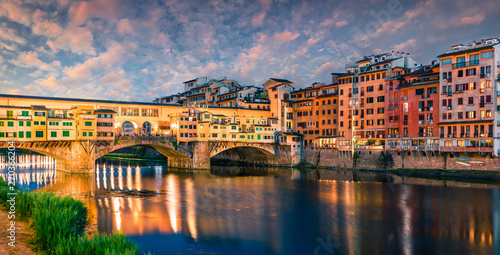 Splendid medieval arched river bridge with Roman origins - Ponte Vecchio over Arno river. Colorful spring sunset view of Florence, Italy, Europe. Traveling concept background. photo
