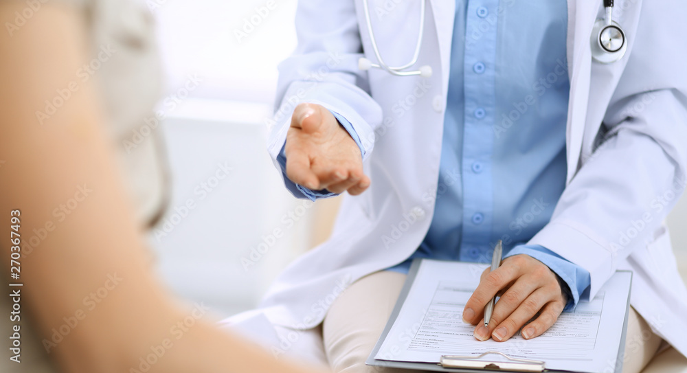 Doctor and patient talking. Physician at work in hospital while writing up medication history records form on clipboard near sitting woman. Healthcare and medicine concepts Doctor and patient talking. Physician at work in hospital while writing up medication history records form on clipboard near sitting woman. Healthcare and medicine concepts