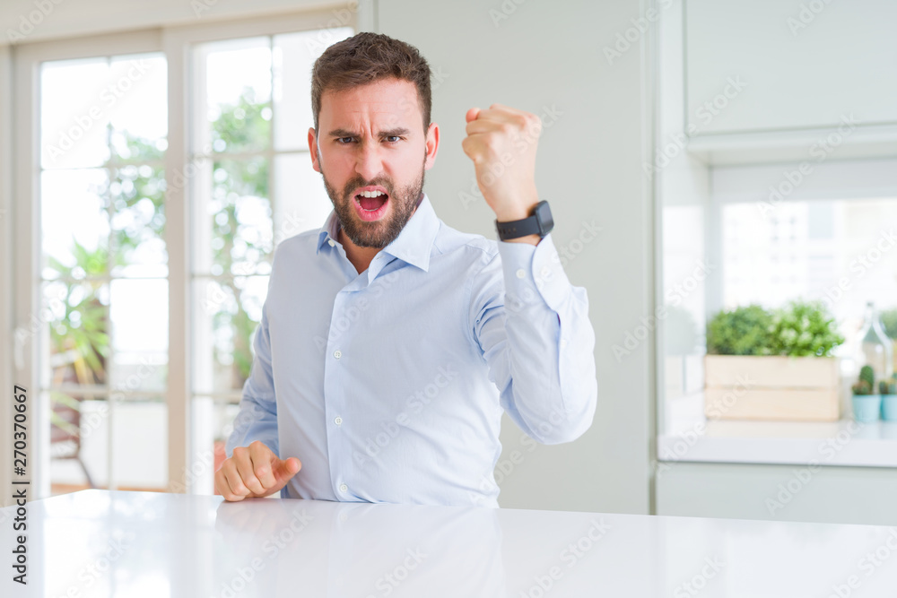 Handsome business man angry and mad raising fist frustrated and furious while shouting with anger. Rage and aggressive concept.