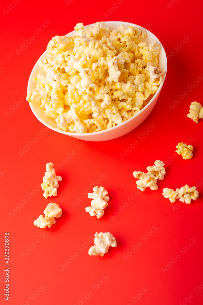 plate with popcorn on a red bright background. movie viewing concept, weekend getaway, with space plate with popcorn on a red bright background. movie viewing concept, weekend getaway, with space