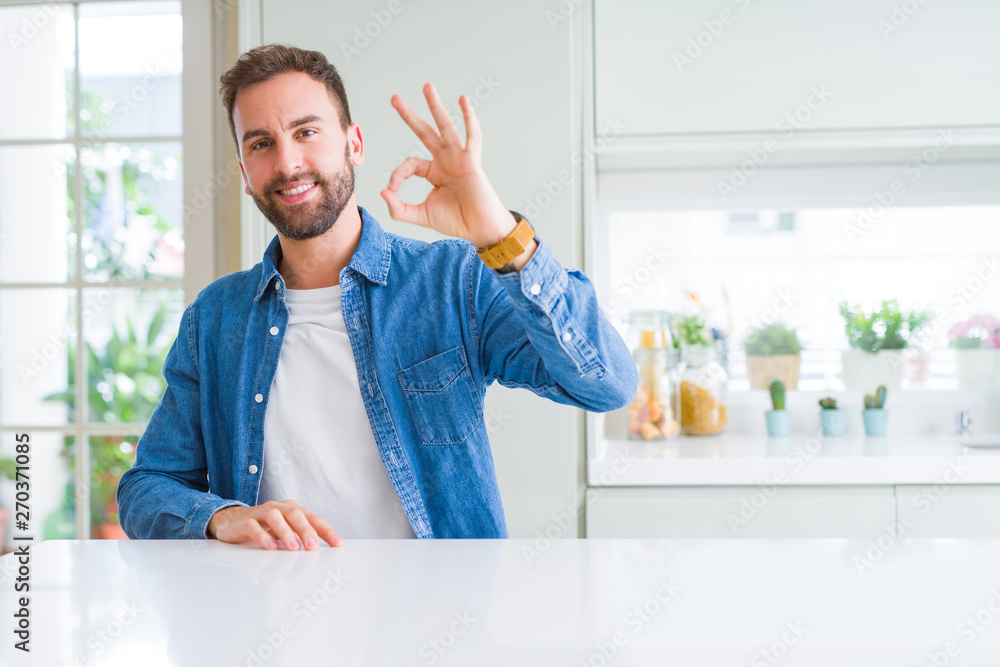 Handsome man at home smiling positive doing ok sign with hand and fingers. Successful expression.