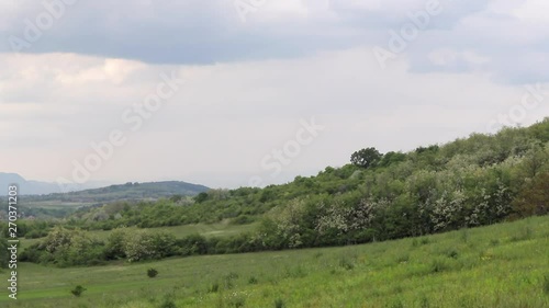 Timelapse across open, green, farmland countryside landscape field with fast moving clouds. Mogyorod, Hungary photo