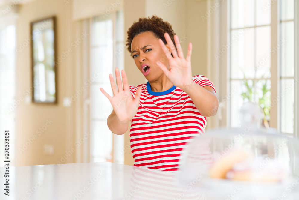 Young beautiful african american woman at home afraid and terrified with fear expression stop gesture with hands, shouting in shock. Panic concept. Young beautiful african american woman at home afraid and terrified with fear expression stop gesture with hands, shouting in shock. Panic concept.