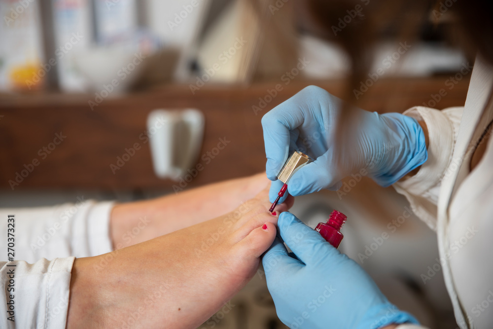 Woman doing the pedicure and stroking the nails red Woman doing the pedicure and stroking the nails red
