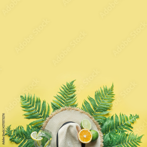 Female beach straw sunhat, citrics on yellow. Top view. Summer travel concept.
