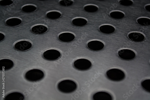 Gray monophonic background with big quantity of holes in a metal plate. Surface. Texture.