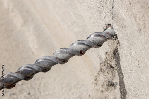 People are using electric drill,He drilled concrete to put steel anchor.