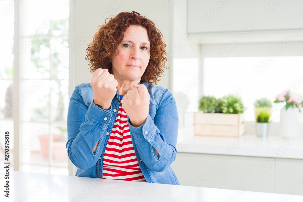 Middle age senior woman with curly hair wearing denim jacket at home Ready to fight with fist defense gesture, angry and upset face, afraid of problem Middle age senior woman with curly hair wearing denim jacket at home Ready to fight with fist defense gesture, angry and upset face, afraid of problem