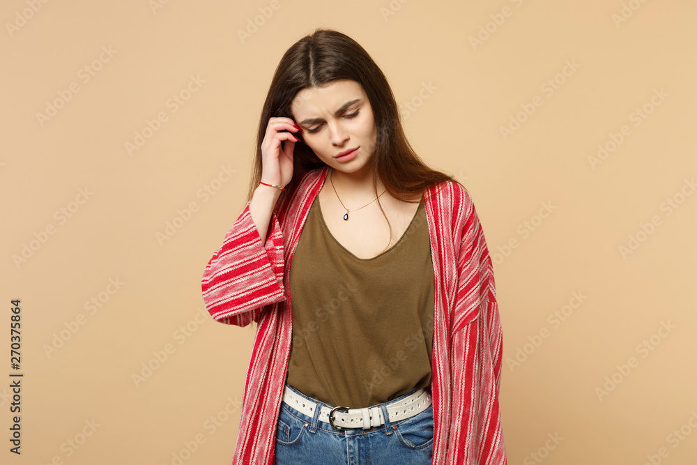 Portrait of preoccupied young woman in casual clothes looking down, putting hand on head isolated on pastel beige background in studio. People sincere emotions, lifestyle concept. Mock up copy space. Portrait of preoccupied young woman in casual clothes looking down, putting hand on head isolated on pastel beige background in studio. People sincere emotions, lifestyle concept. Mock up copy space.