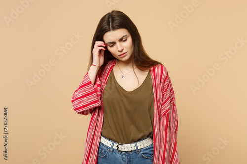 Portrait of preoccupied young woman in casual clothes looking down, putting hand on head isolated on pastel beige background in studio. People sincere emotions, lifestyle concept. Mock up copy space. © ViDi Studio