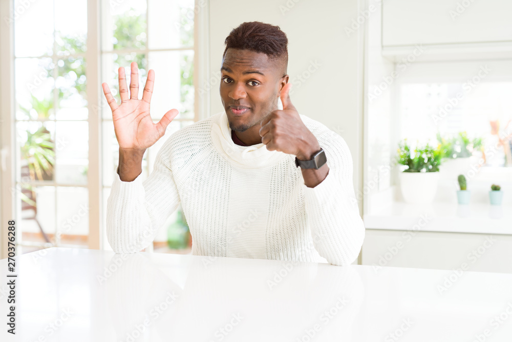 Handsome african american man on white table showing and pointing up with fingers number six while smiling confident and happy. Handsome african american man on white table showing and pointing up with fingers number six while smiling confident and happy.