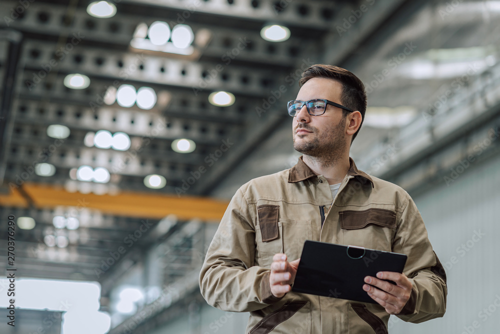 Portrait of a handsome foreman at manufacturing plant, close-up, low angle view. Portrait of a handsome foreman at manufacturing plant, close-up, low angle view.