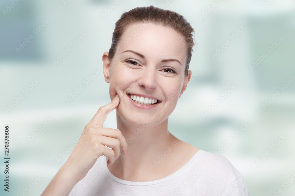 young woman with white teeth smiles happily in front of a dentist room young woman with white teeth smiles happily in front of a dentist room