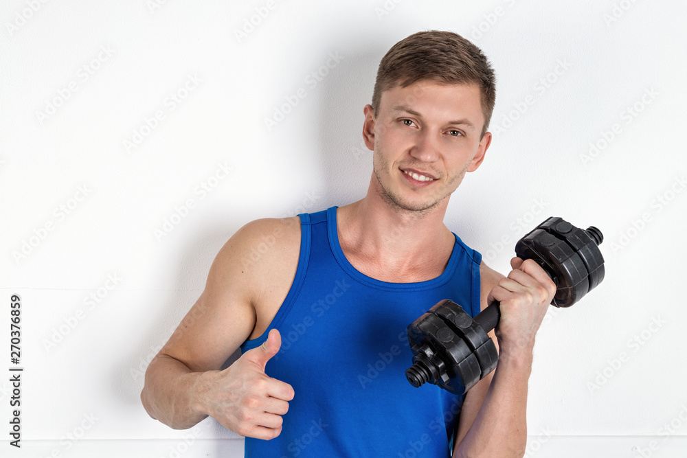 Handsome young man in blue shirt lifting dumbbell. White background Handsome young man in blue shirt lifting dumbbell. White background